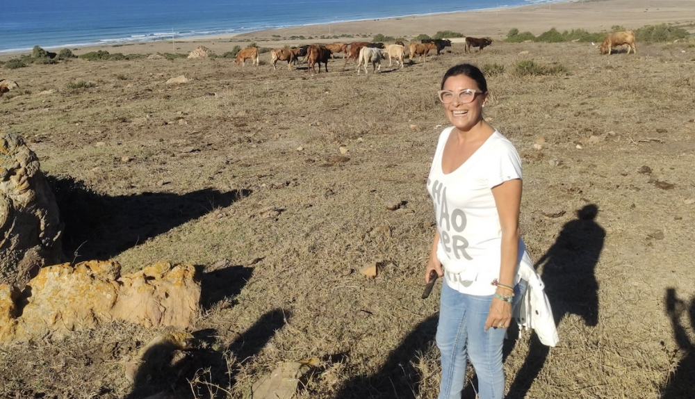 La delegada municipal posando ante ganado suelto en una finca. 
