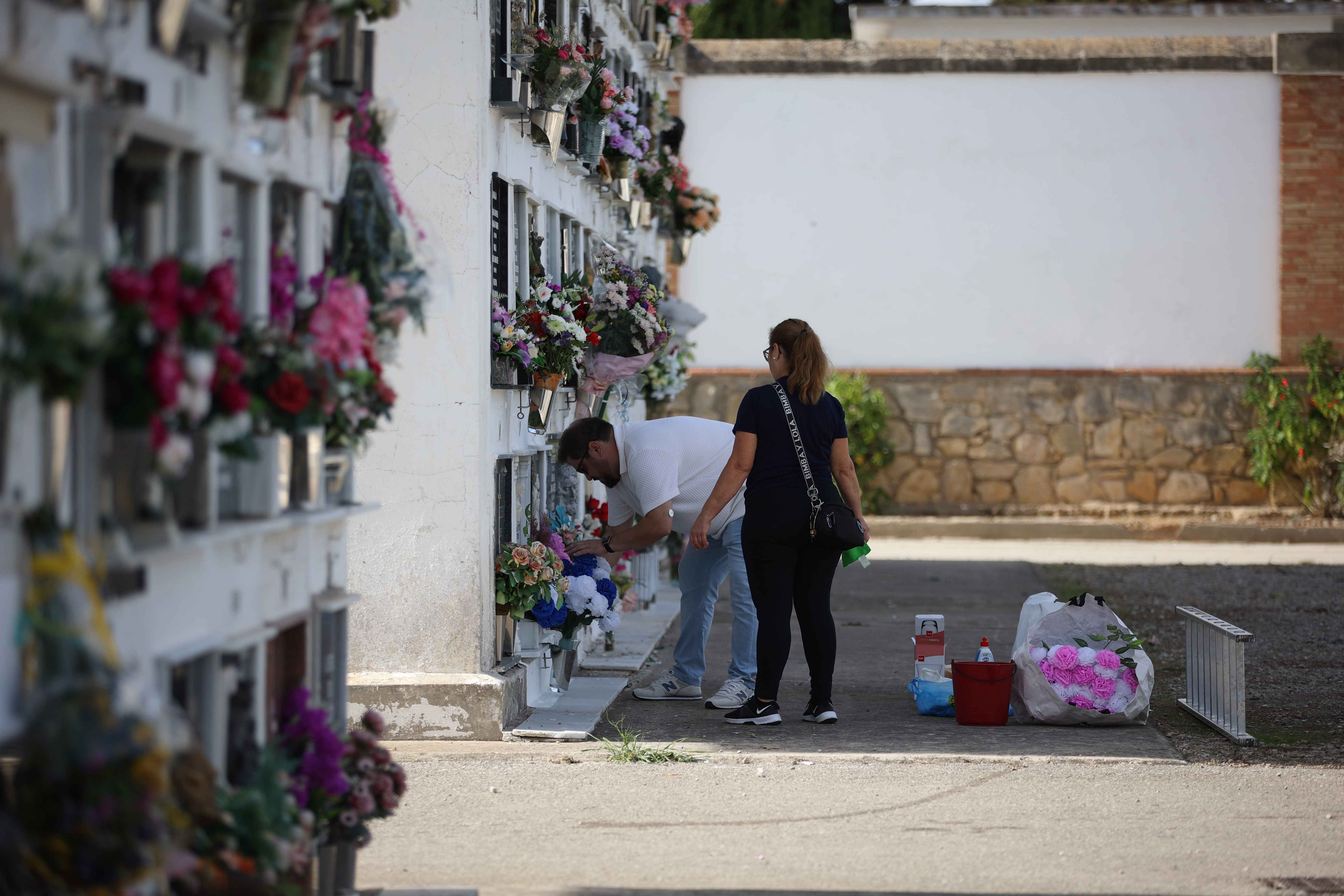 Dos personas colocando flores a un ser querido. 