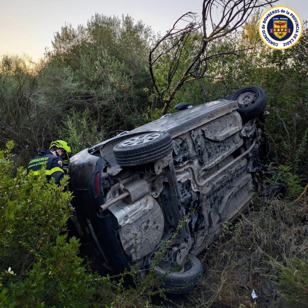 El vehículo, de lado fuera de la carretera.