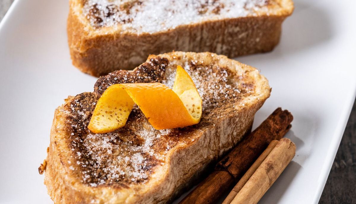 torrijas caseras tradicionales espanolas decoradas con canela y cascara de naranja sobre mesa de madera
