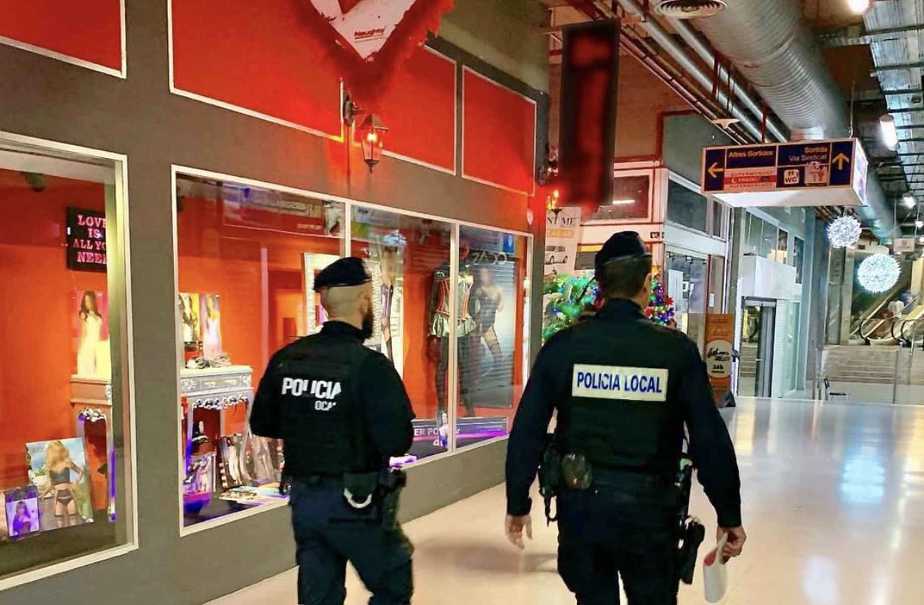 Imagen de dos policías pasando por delante de una tienda erótica.