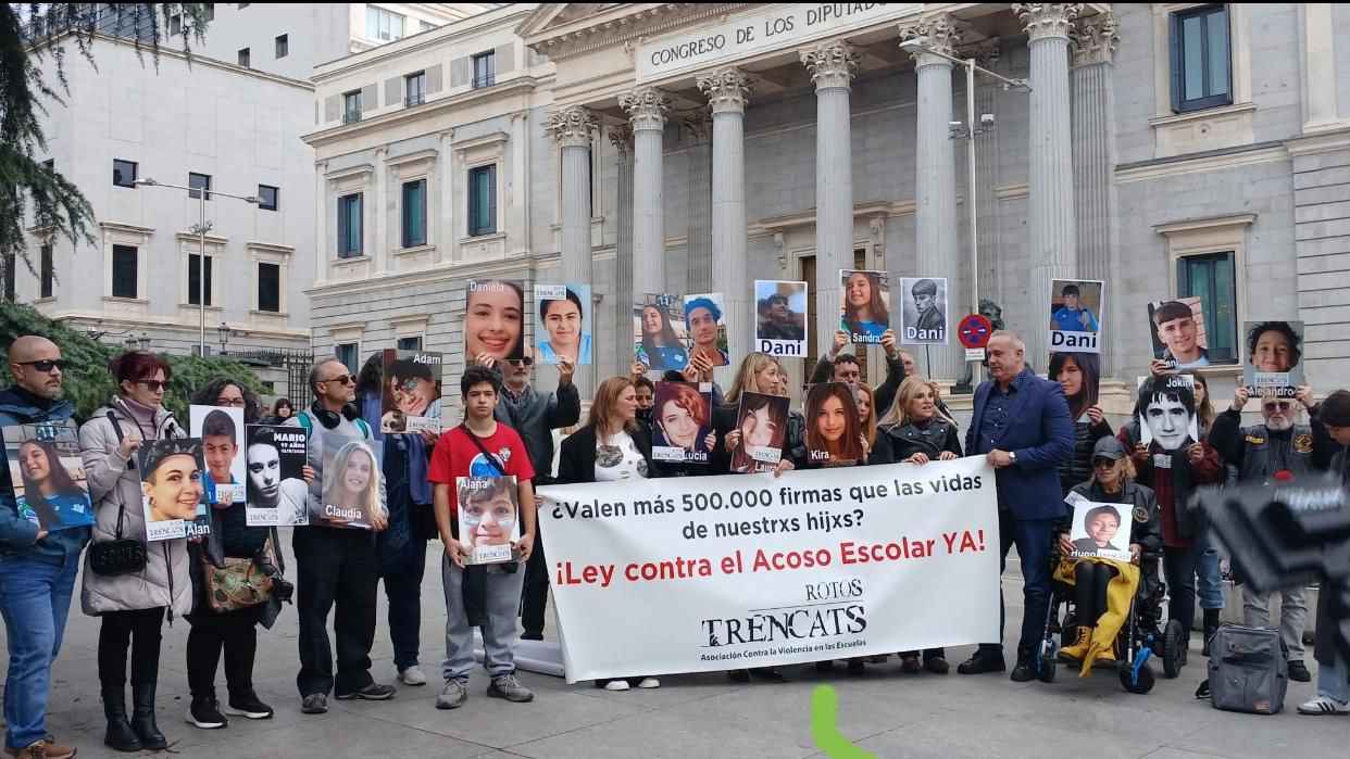 Integrantes de Trencats y familiares de víctimas posan frente al Congreso de los Diputados sosteniendo retratos de sus hijas e hijos. Integrantes de Trencats y familiares de víctimas posan frente al Congreso de los Diputados sosteniendo retratos de sus hijas e hijos.