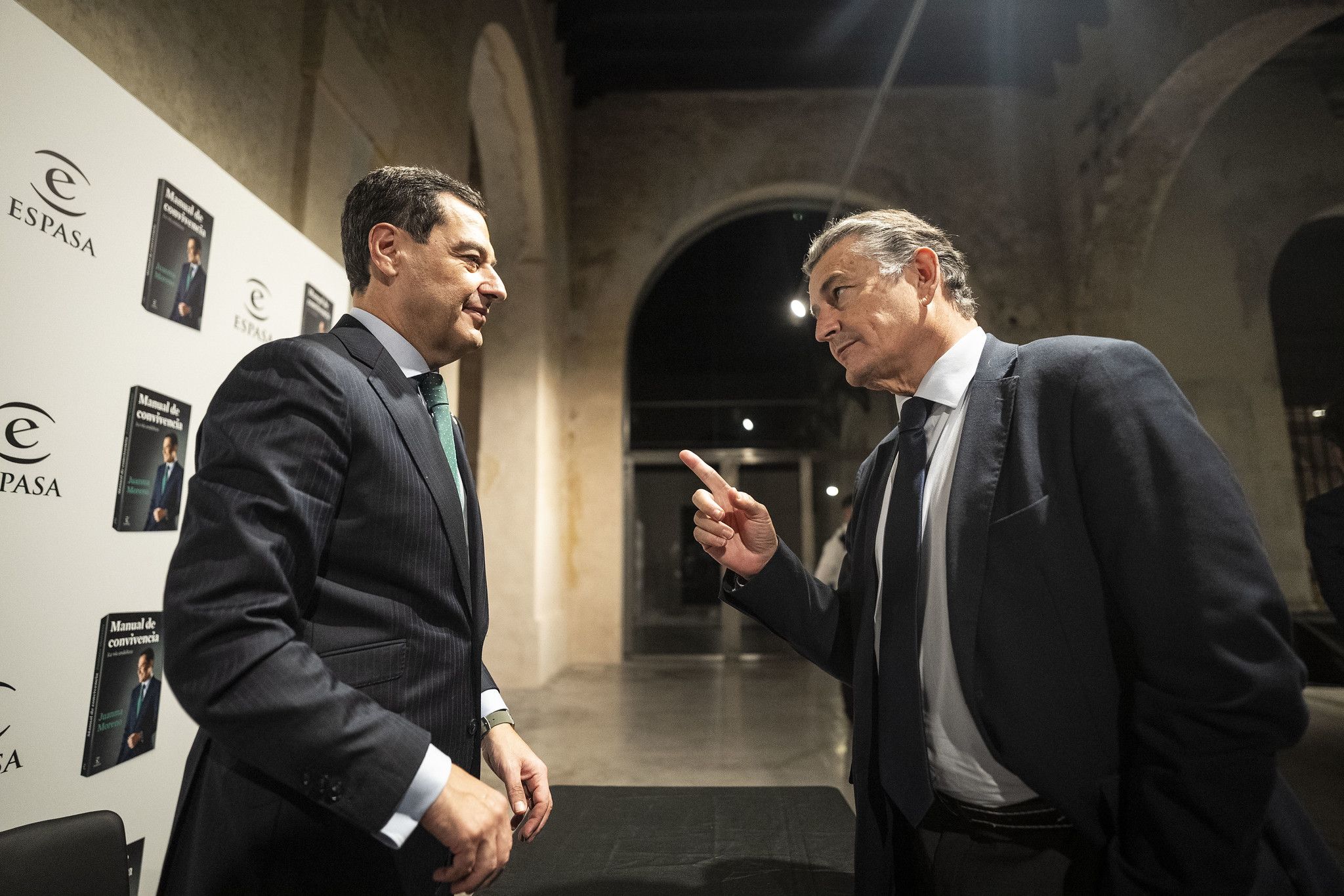 El consejero de Sanidad, Antonio Sanz, habla con el presidente Juanma Moreno durante una presentación de su libro.