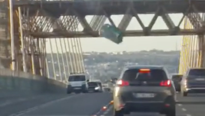 Imagen del baño portátil cayendo en el puente del Centenario de Sevilla.
