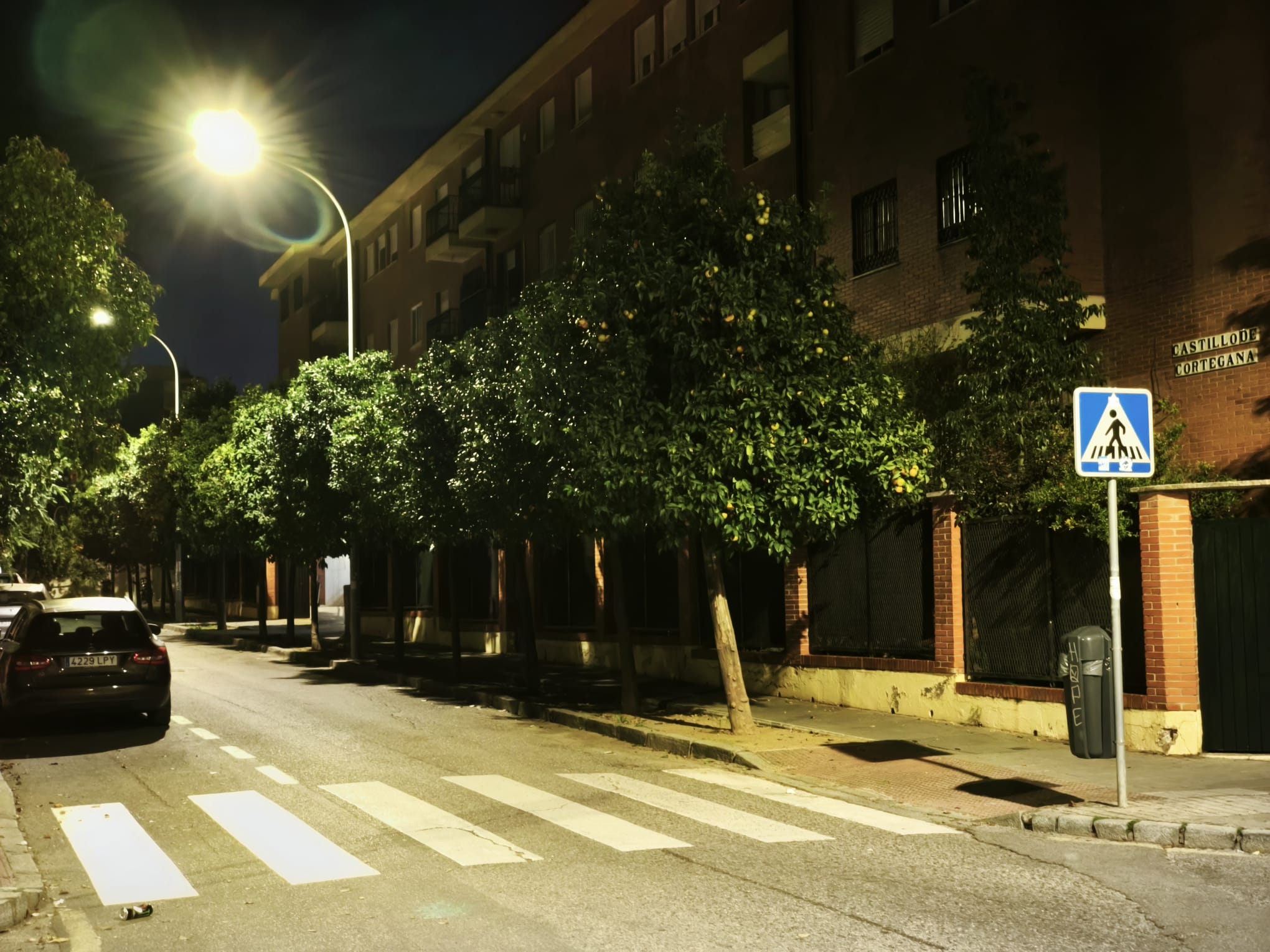 La iluminación artificial denota la oscuridad en la acera frente a la calzada.