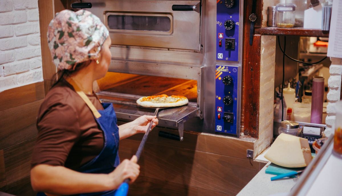 Digna introduce la pizza en el horno.