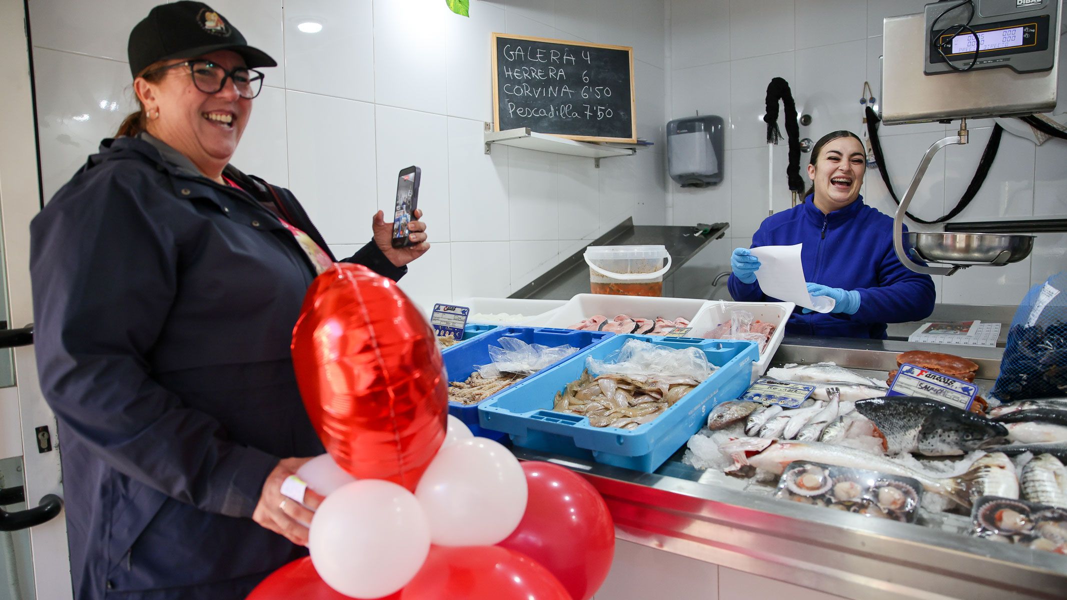 Conchi Falcón, de Creamos sonrisas, sorprende a la portuense Clara, en la pescadería en la que trabaja en El Puerto. 
