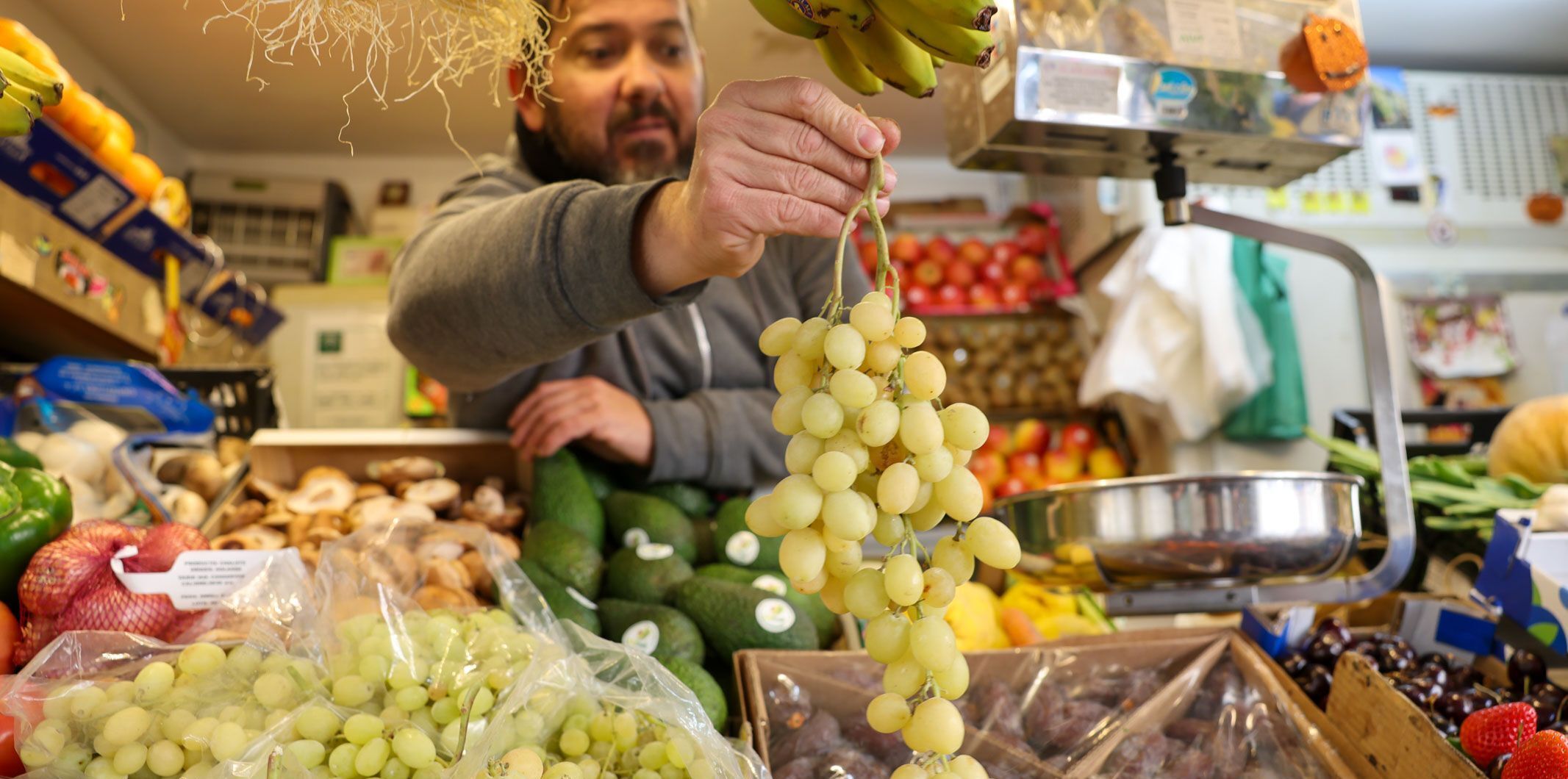 Ismael Sánchez, con un racimo de uvas en su puesto del Mercado de Abastos de Cádiz.