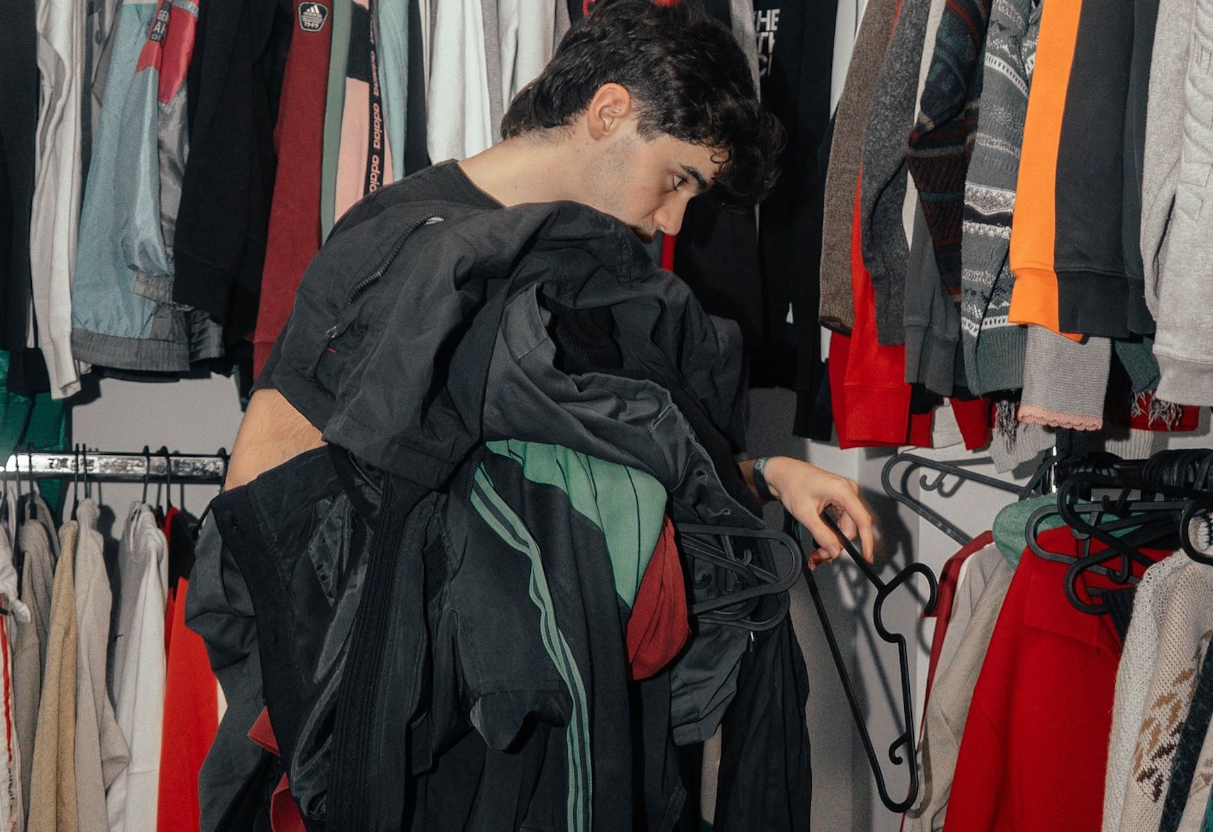 Un chico mira las prendas del mercado vintage.