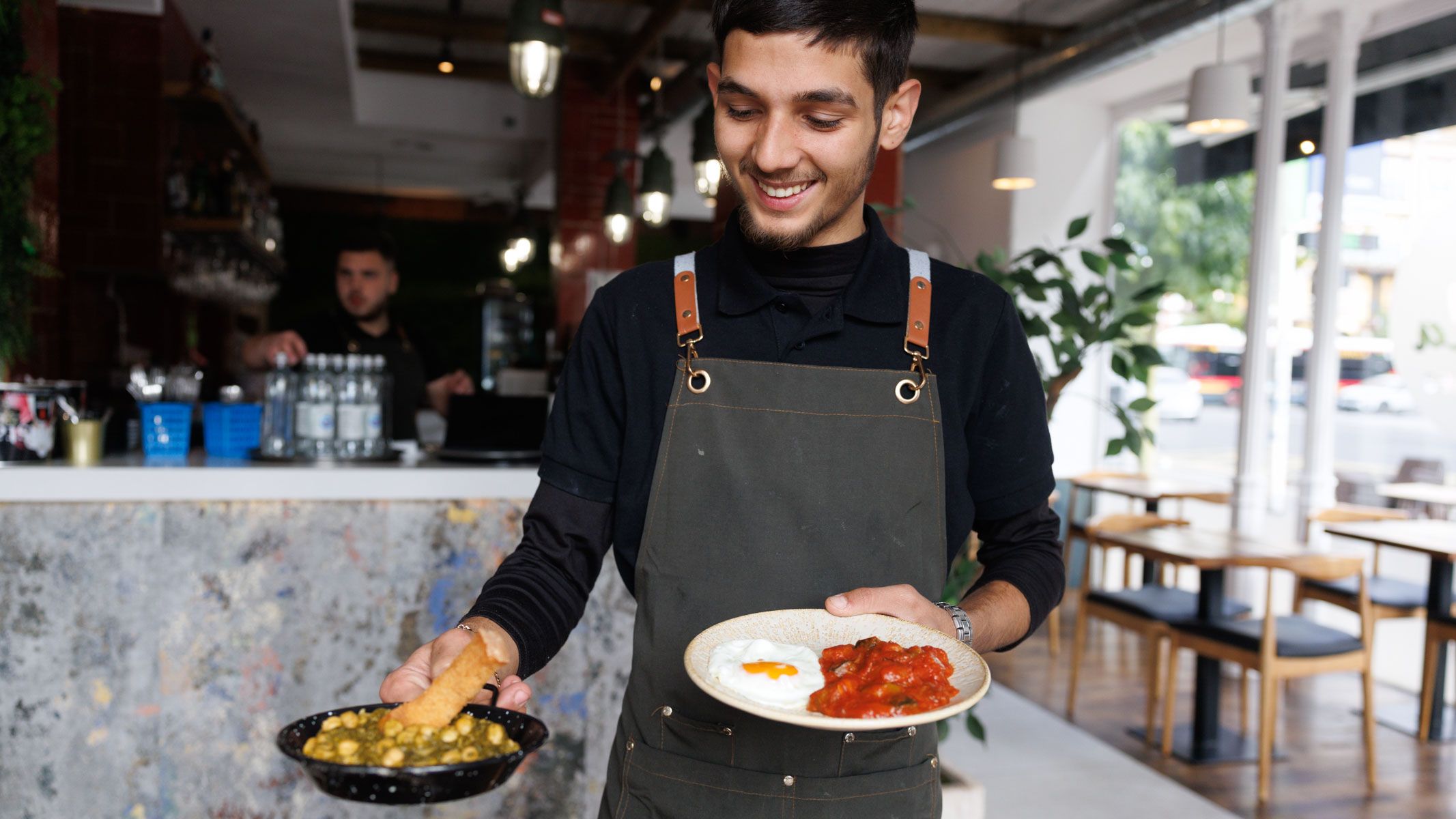 Uno de los camareros de La Gorda de los Jardines muestra dos tapas típicas de la casa.