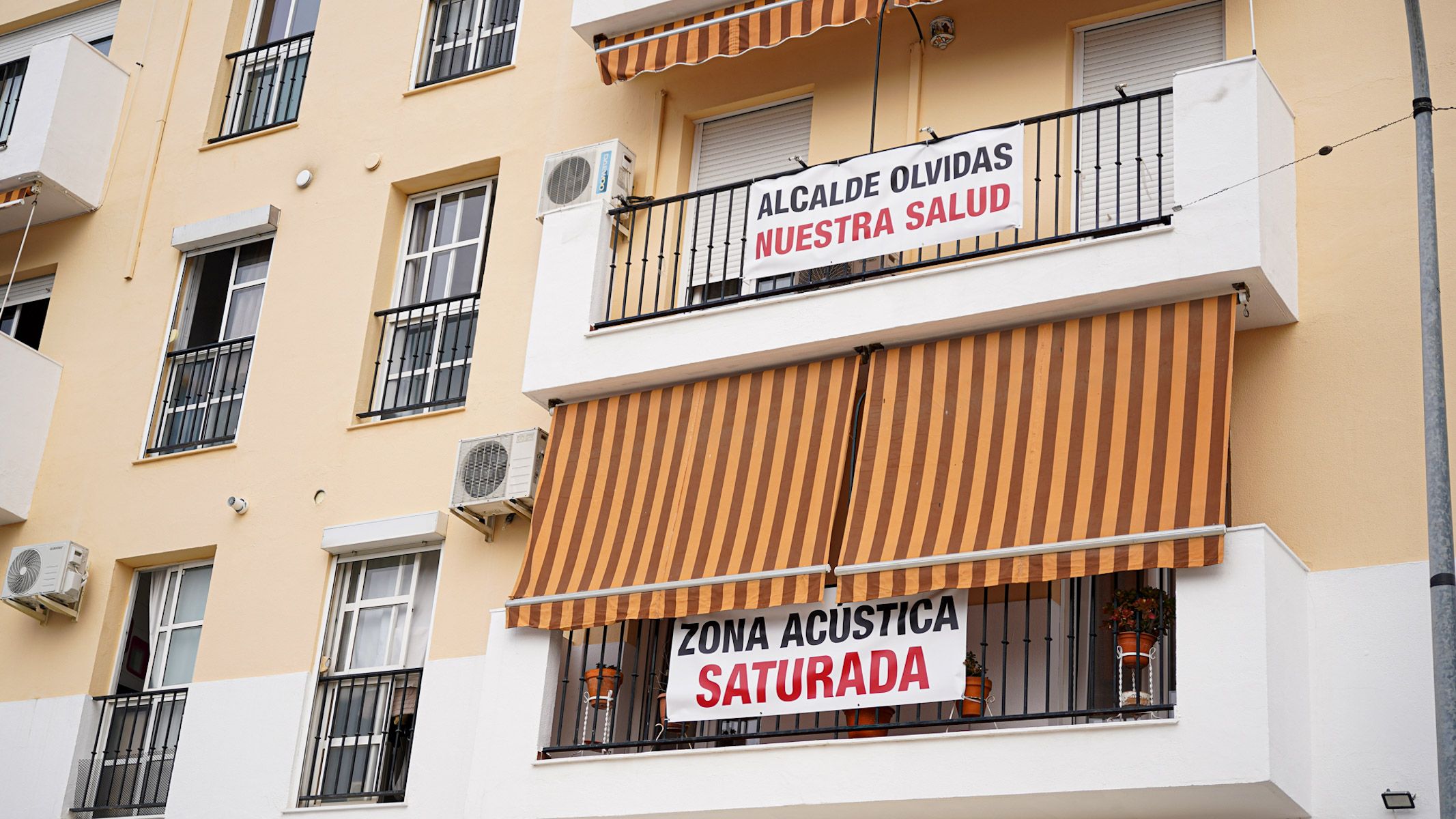 Algunos vecinos muestran en sus terrazas carteles de protesta por la contaminación acústica en Sevilla.