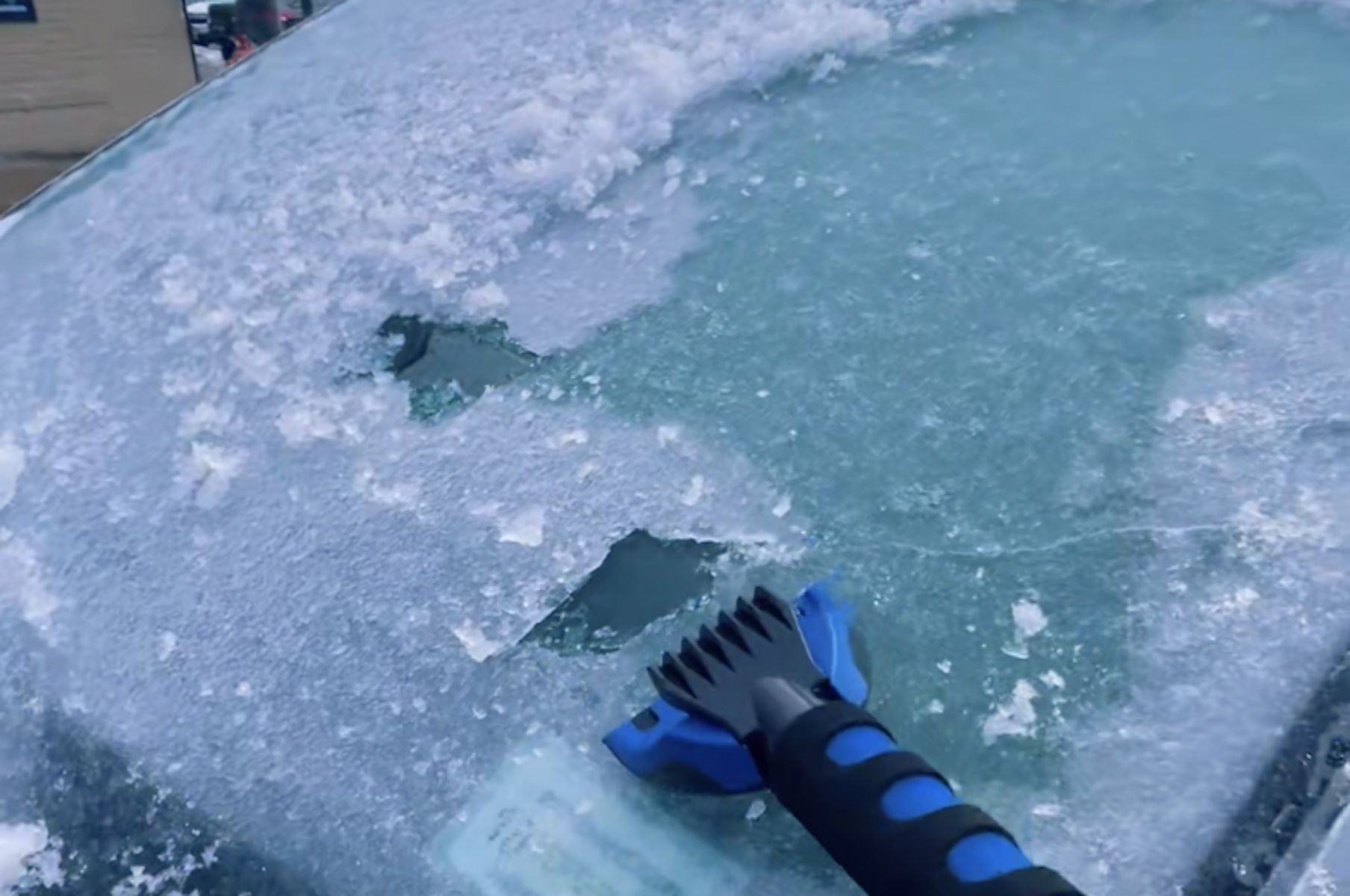 Un rascador de plástico sobre un parabrisas congelado.