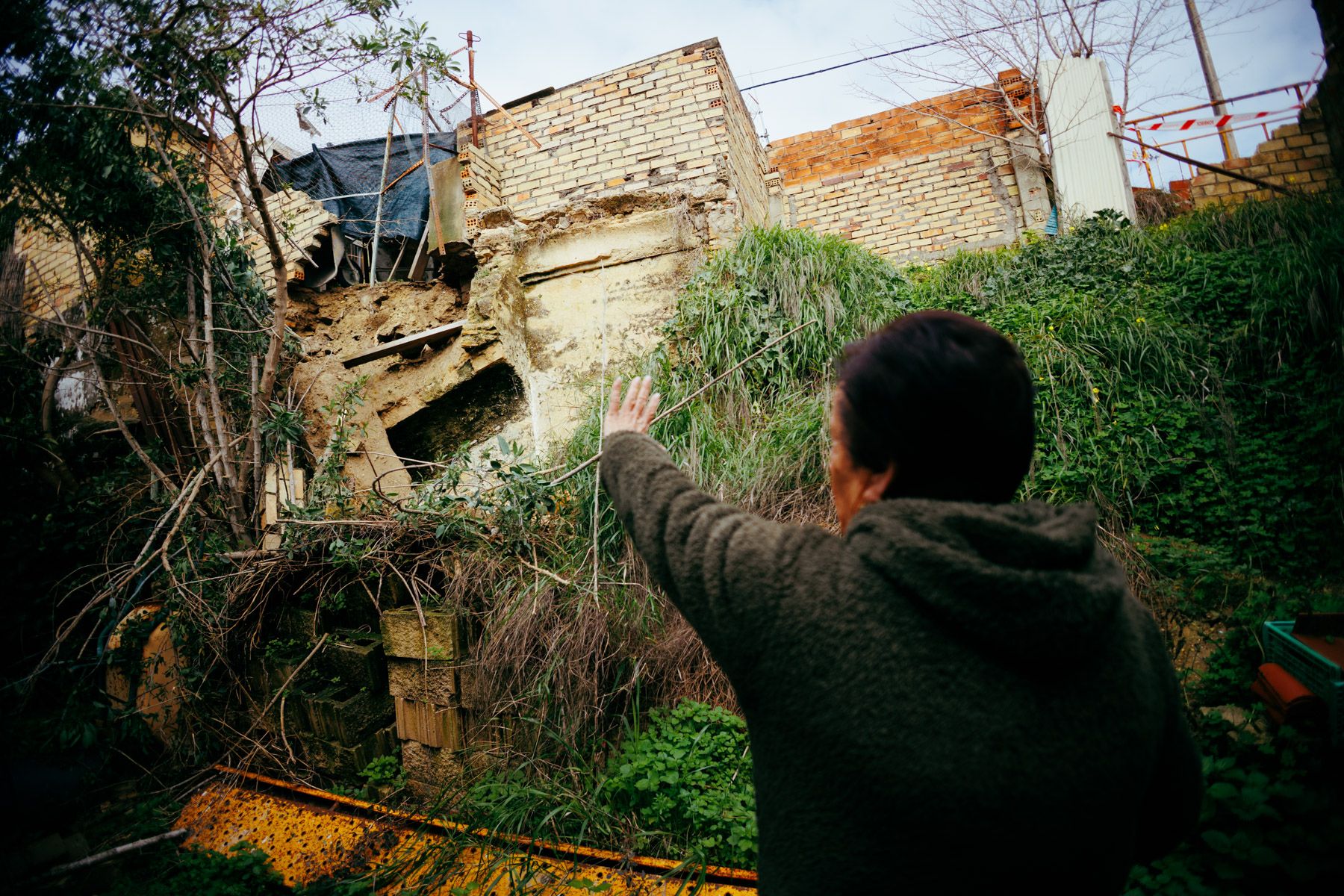 La vecina de Los Albarizones afectada por el derrumbe, señalando los daños.
