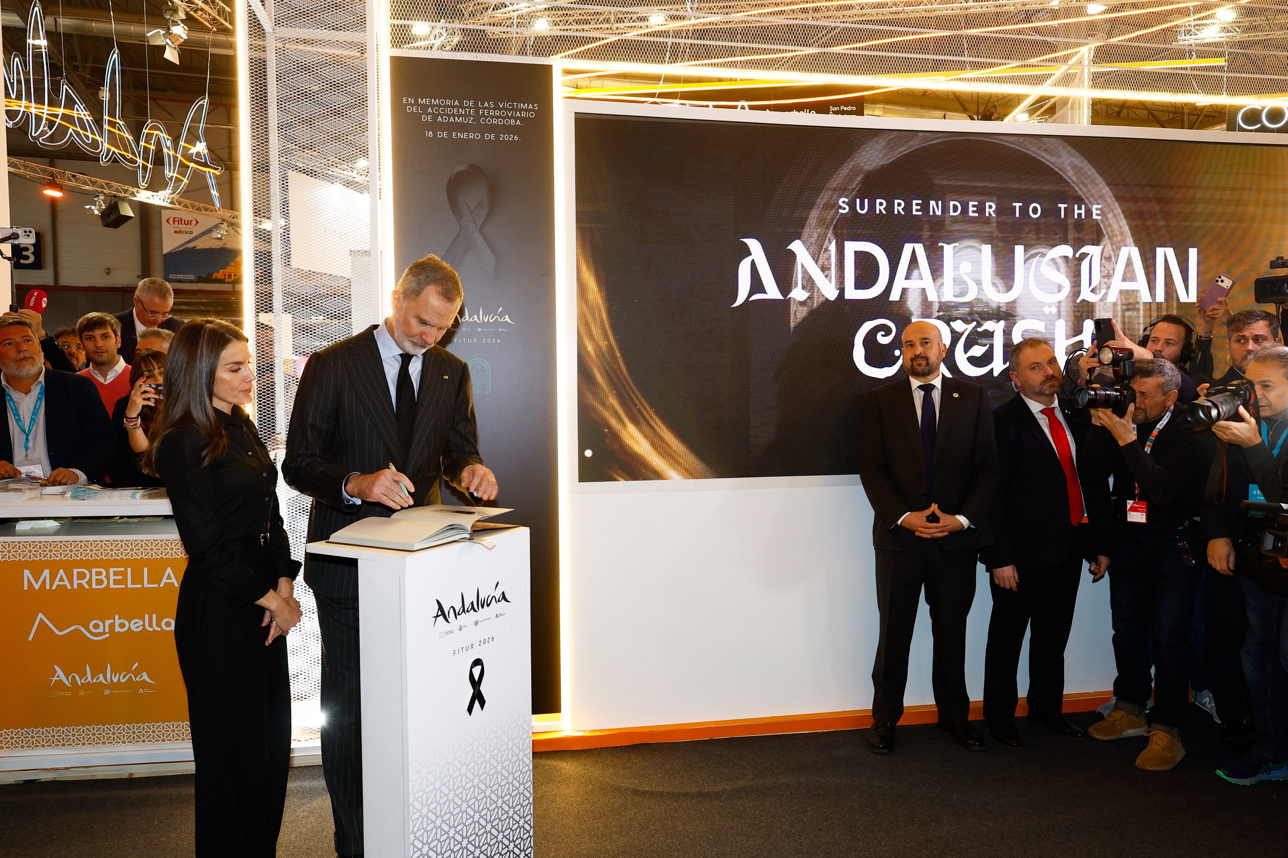 Los reyes firman en el libro de condolencias del stand de Andalucía en Fitur 2026, este jueves.