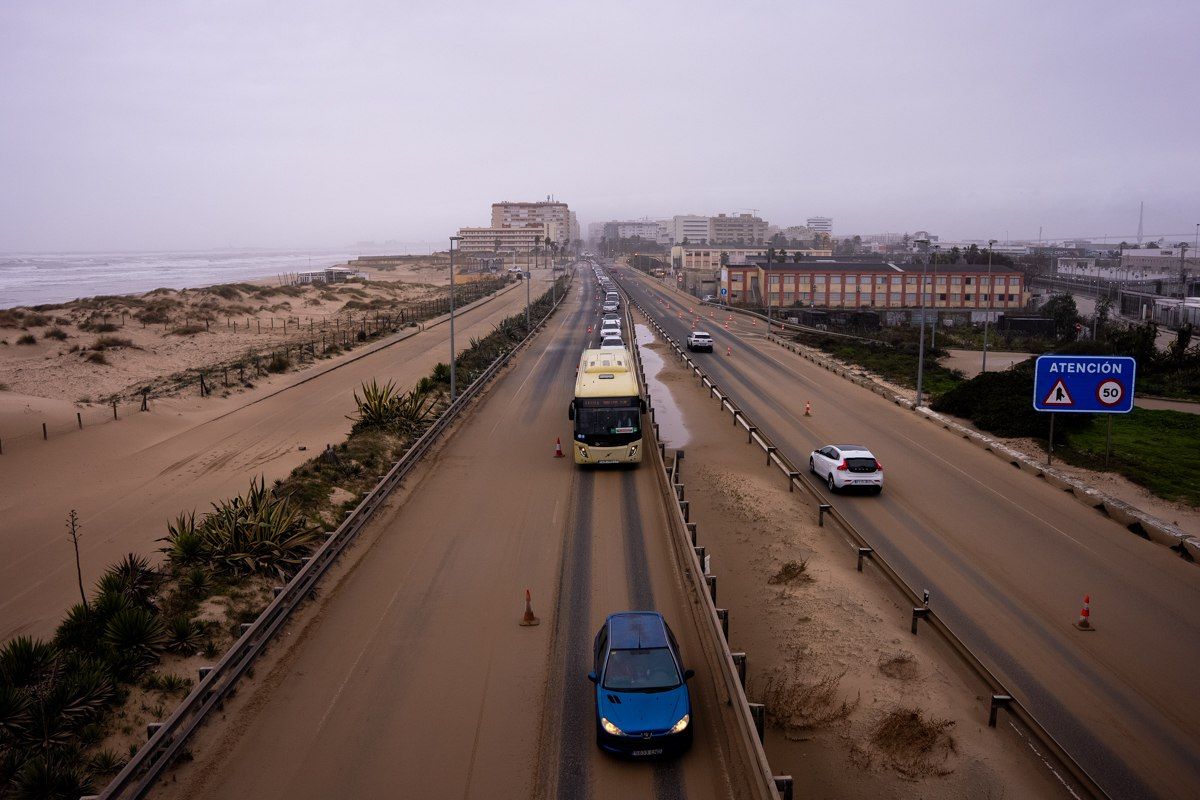 La arena de la playa de Cortadura invade la autovía de Cádiz a San Fernando por el fuerte viento.