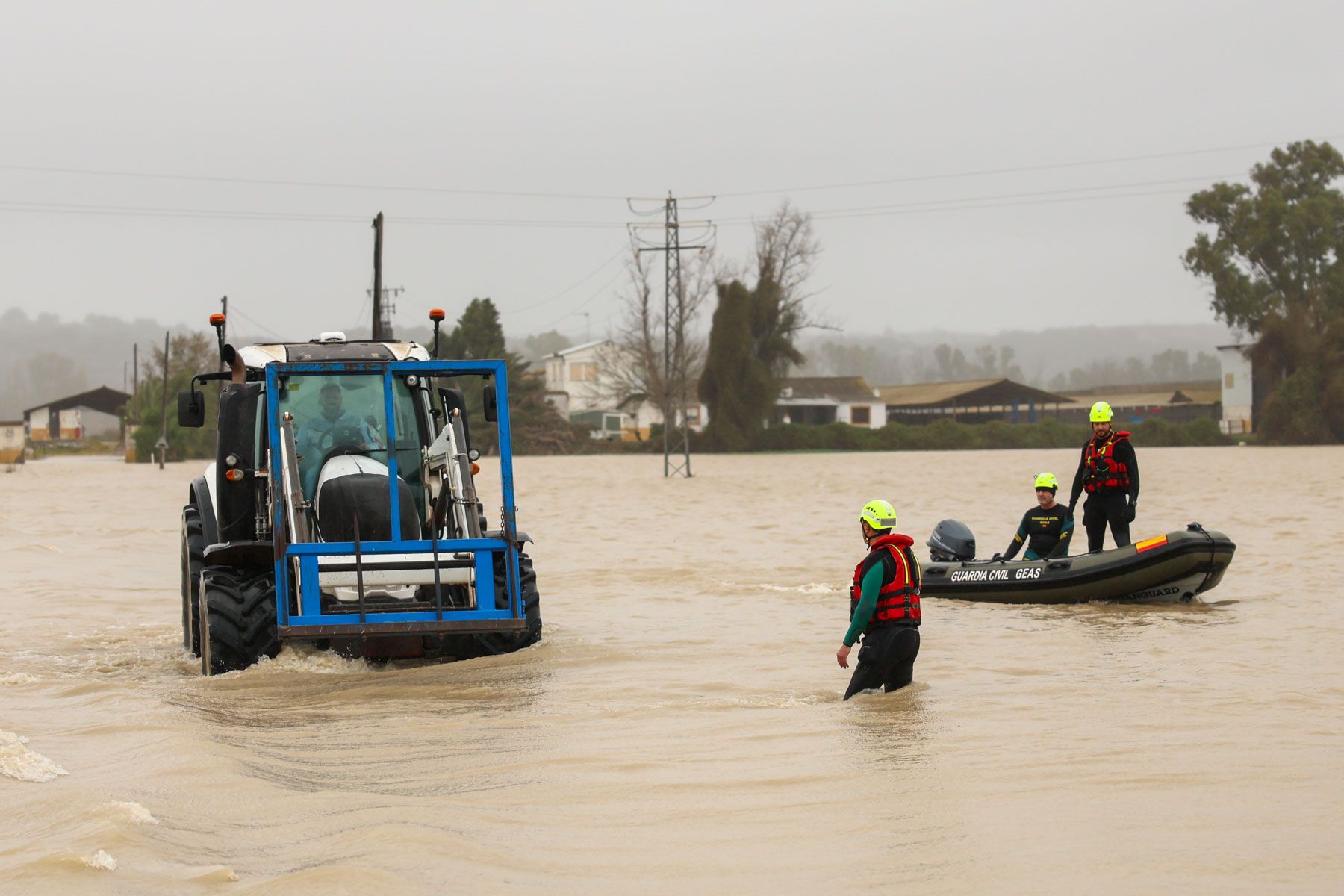 Equipos de emergencia tratan de auxiliar a una persona atrapada en su tractor en medio de la riada.