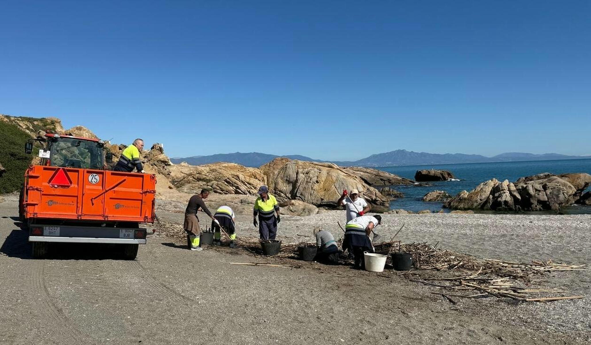 Trabajadores en una playa en Manilva este martes, en camiseta.