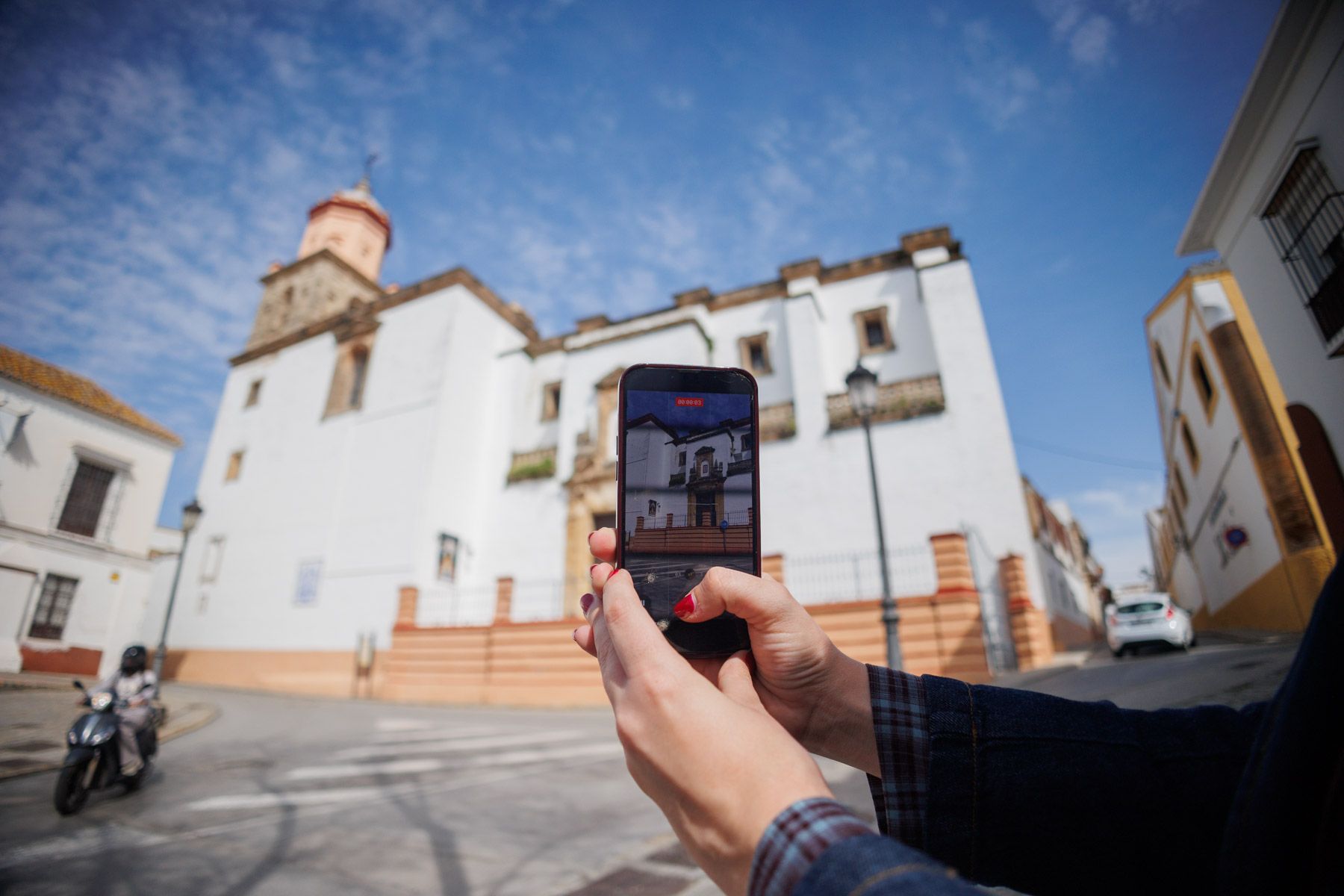 Una mujer haciendo una fotografía de la basílica de Nuestra Señora de la Caridad, en Sanlúcar.
