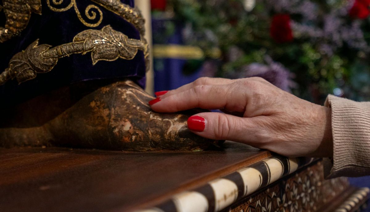 Mano de una devota sobre el pie de Jesús Nazareno.