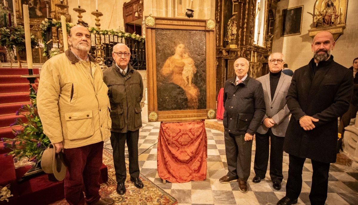 Ex hermanos mayores de La Borriquita y el párroco de San Marcos posando junto al lienzo. 