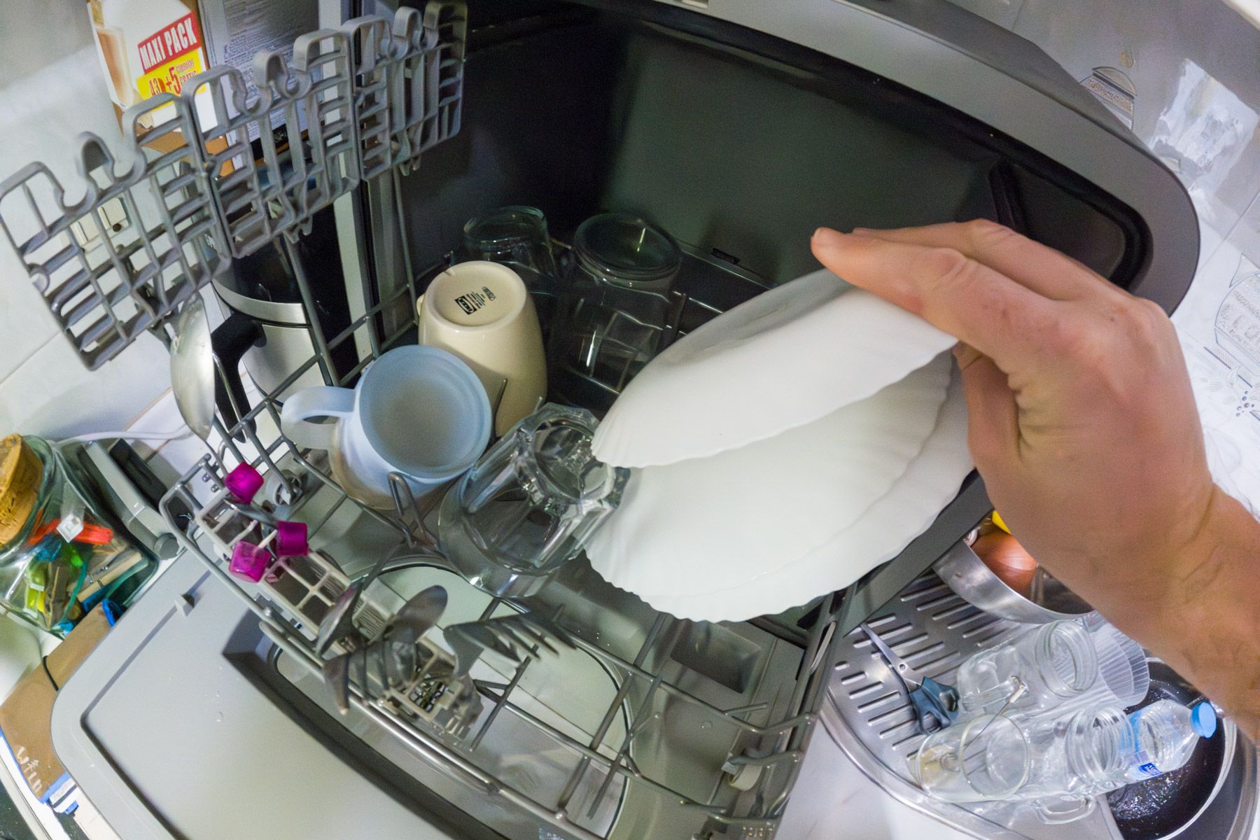 Un hombre pone un lavavajillas en su casa, en horas de menor coste eléctrico.