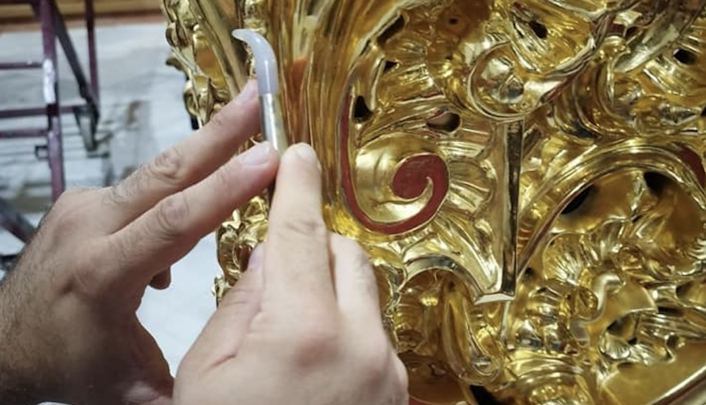 El dorador con la piedra de ágata en el trabajo de bruñir el pan de oro. 