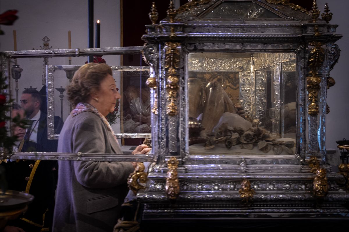 Una devota ante el Cristo Yacente del Santo Entierro en su urna. 