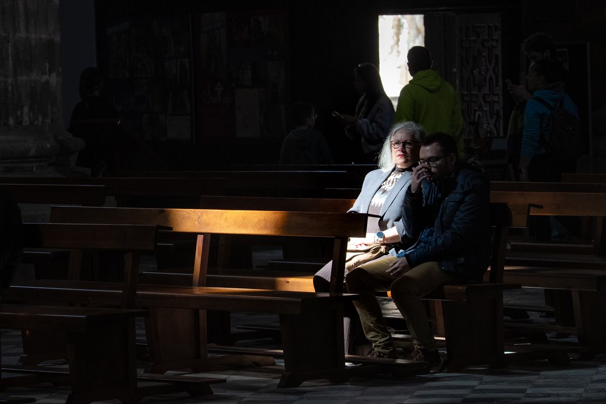 Dos personas sentadas en la Catedralen la veneración del Crucificado  