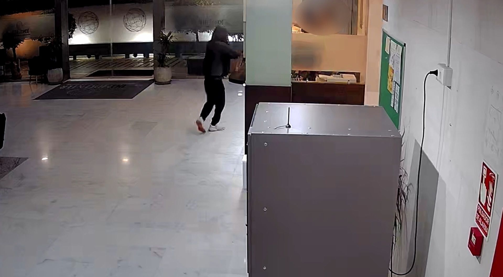 El encapuchado intentando robar en la recepción.