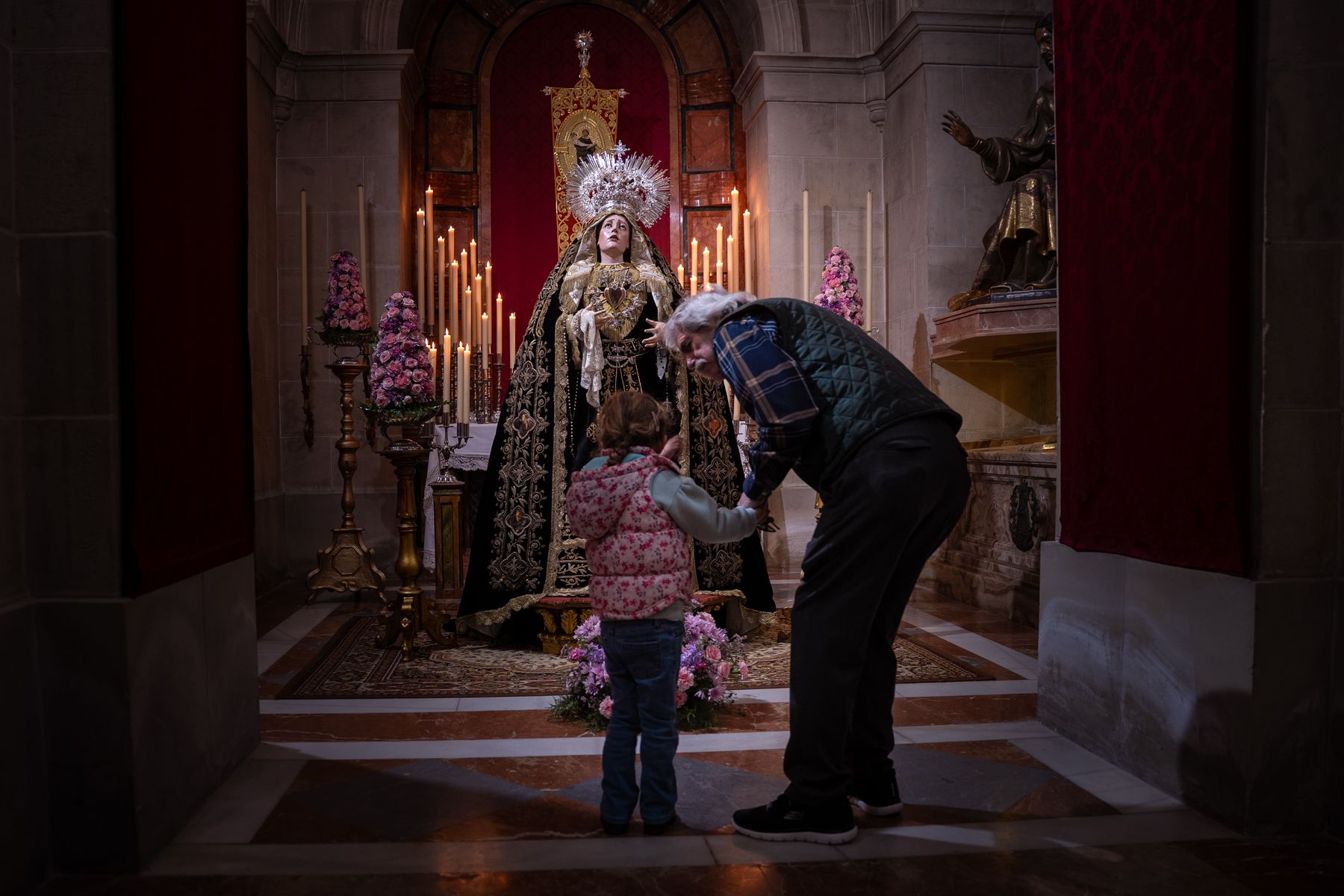 Una pequeña ante la Virgen de Gracia y Esperanza en el Carmen. 
