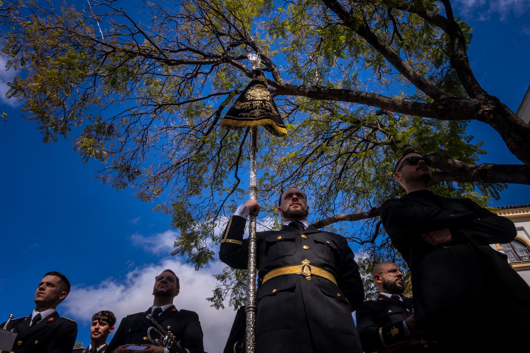 El banderín abriendo marcha a la banda Virgen de los Reyes. 