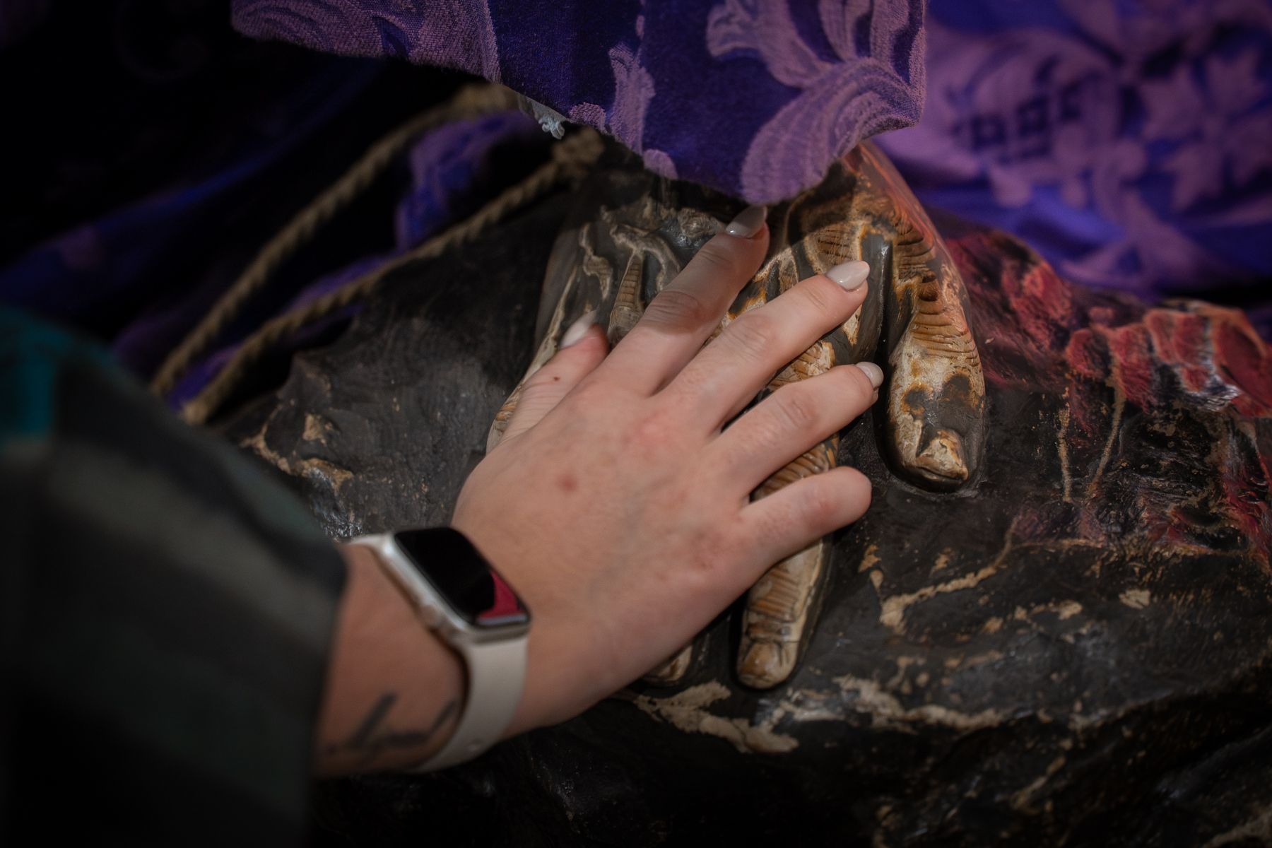 Una devota tocando el pie de la imagen.  