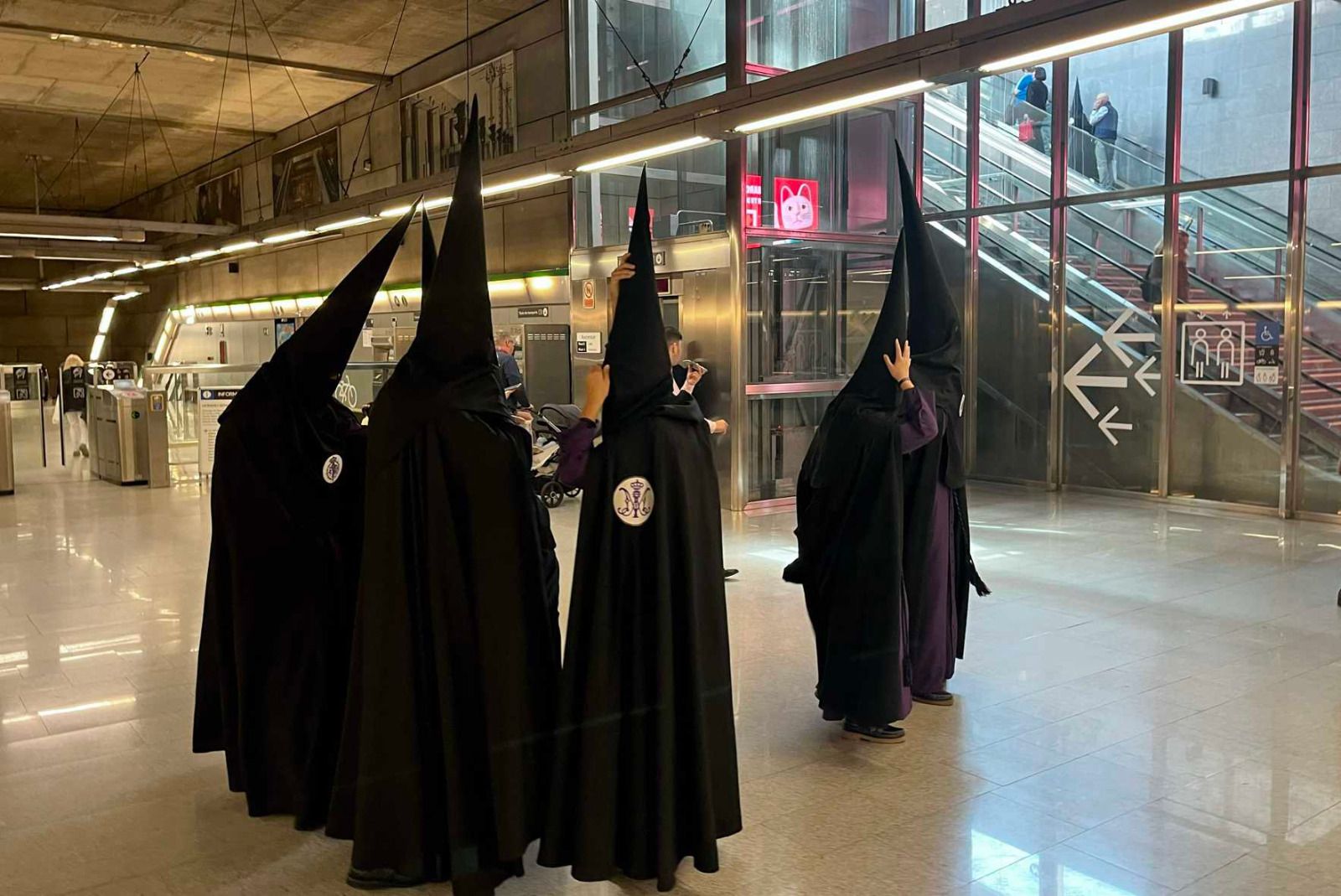 Nazarenos de Sevilla en una estación de metro. 