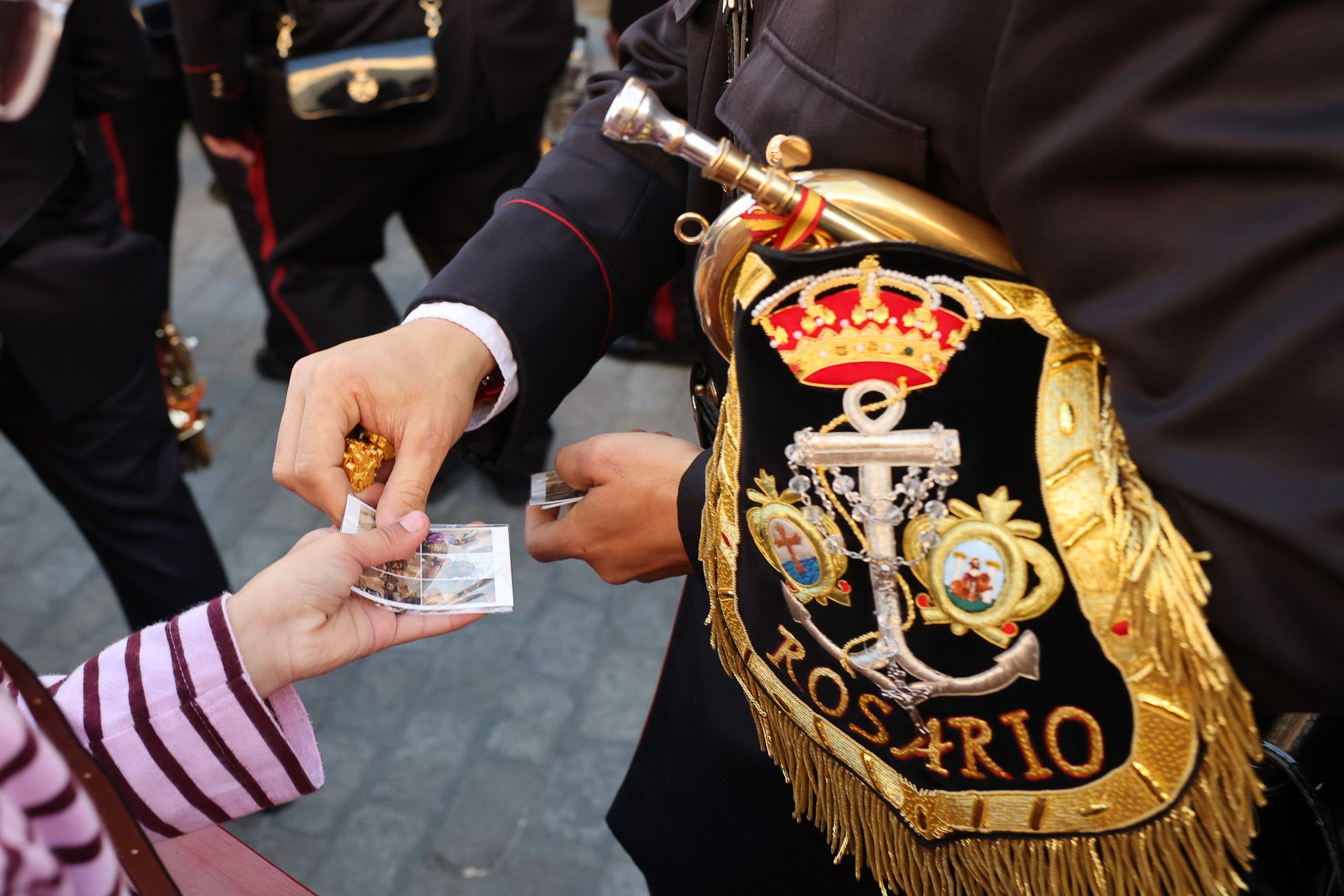 Un músico de la banda del Rosario, entregando una estampa. 