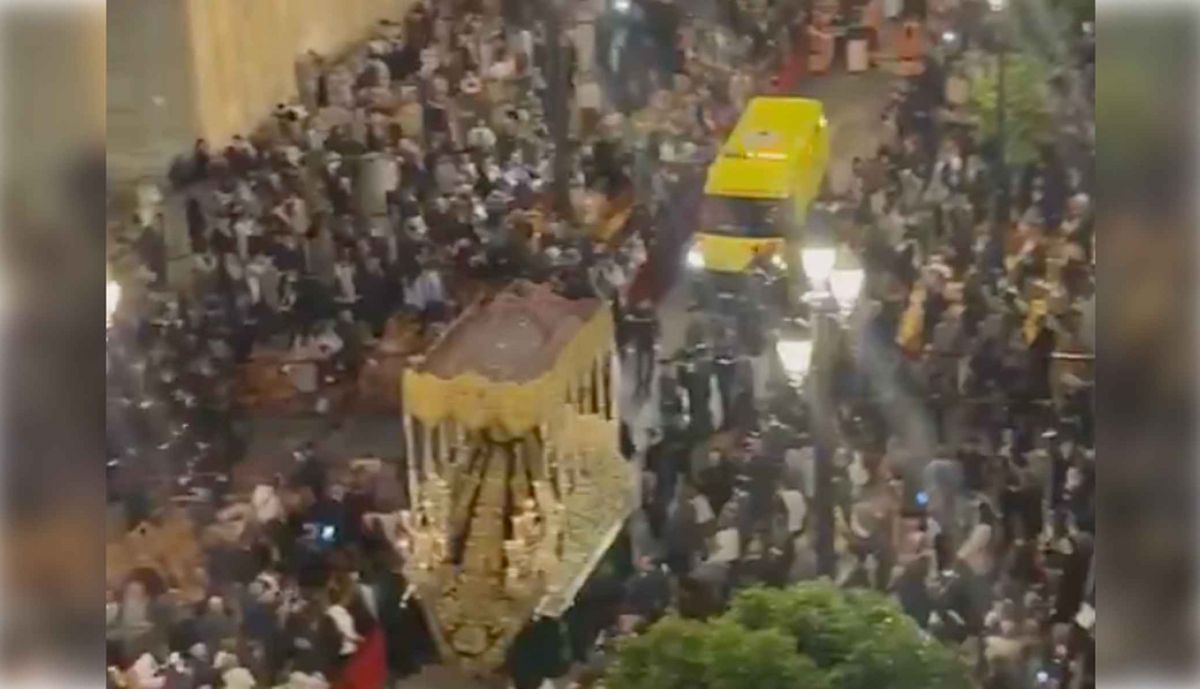 El palio de Gracia y Esperanza, andando para atrás, para que pase una ambulancia.