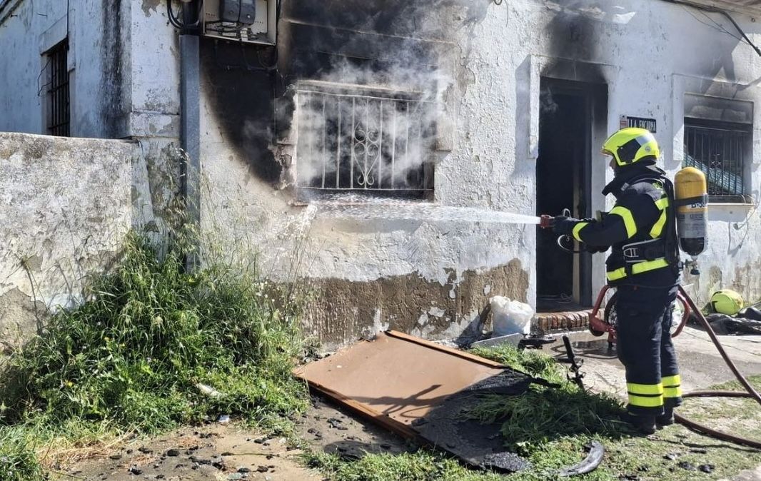 Un bombero extingue las llamas en la casa deshabitada de Puerto Real.