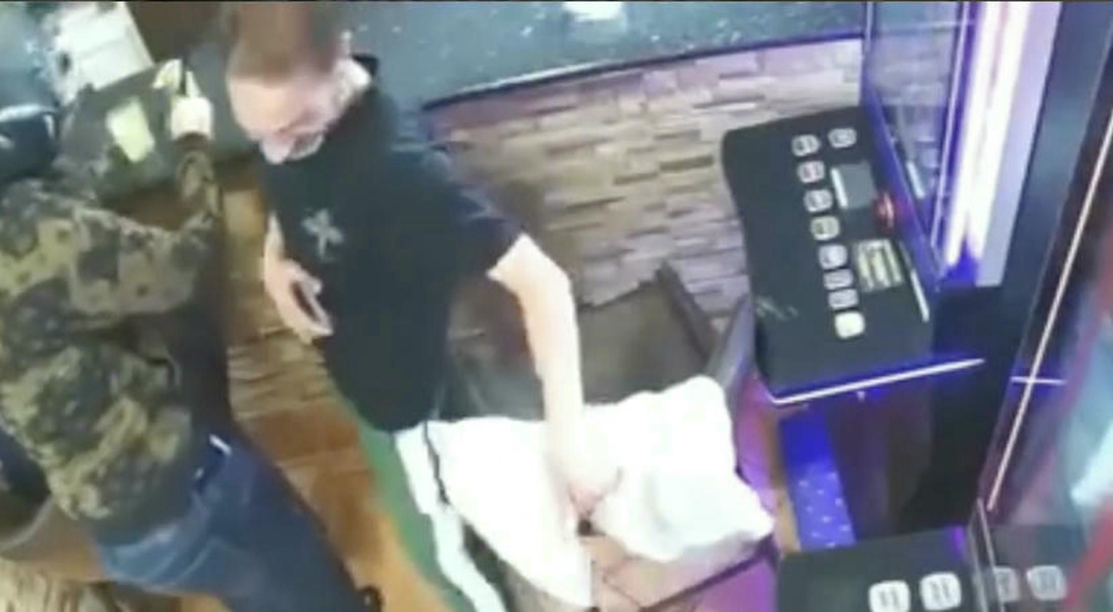 Un cliente pasa al lado del atracador, que porta un machete. Un cliente pasa al lado del atracador, que porta un machete.