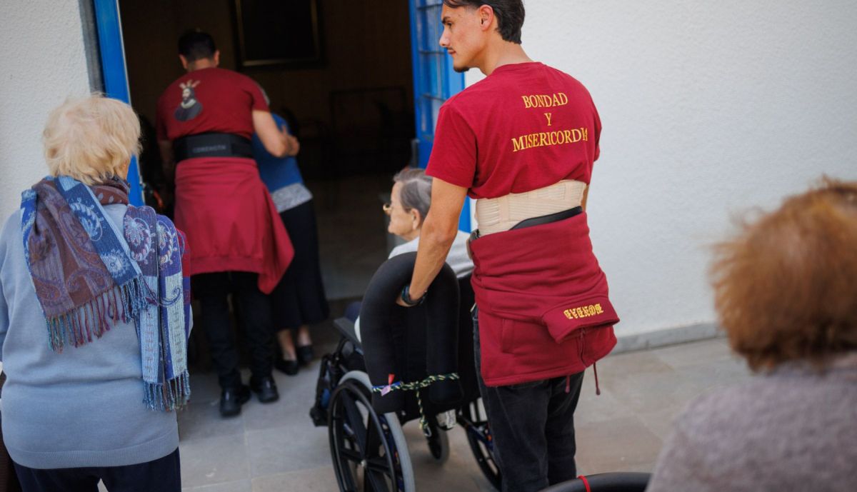 Un costalero llevando a una anciana al interior del geriátrico. 