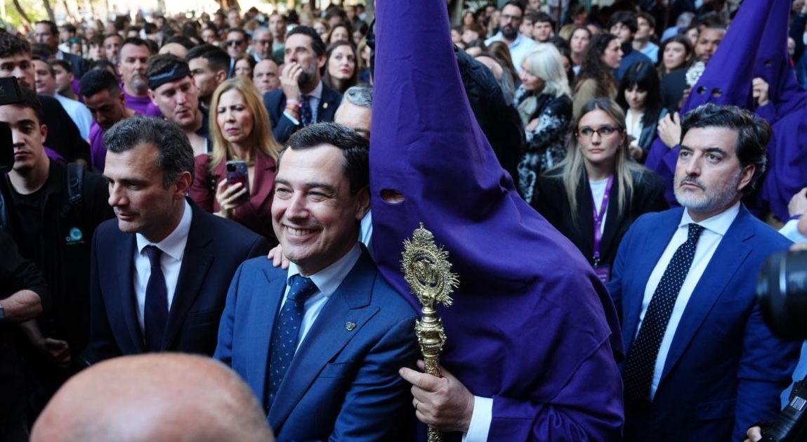 El presidente de la Junta de Andalucía, Juanma Moreno, conversando con un penitente de Columna en el Martes Santo de Cádiz.