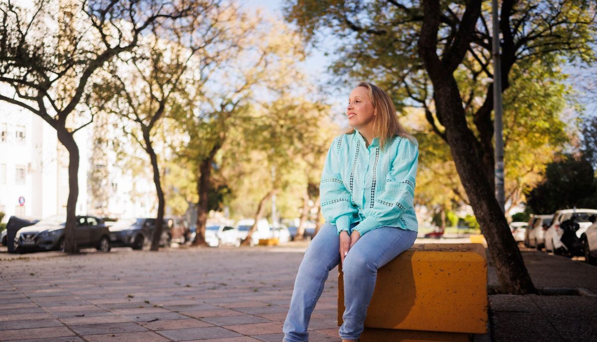 María Zarzuela sentada en un banco en una zona verde de la ciudad. 