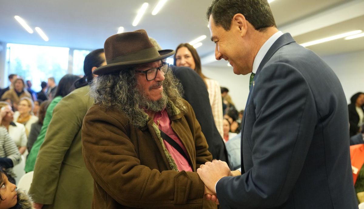 Juanma Moreno, presidente de la Junta, saluda al músico sevillano Raimundo Amador durante el acto.