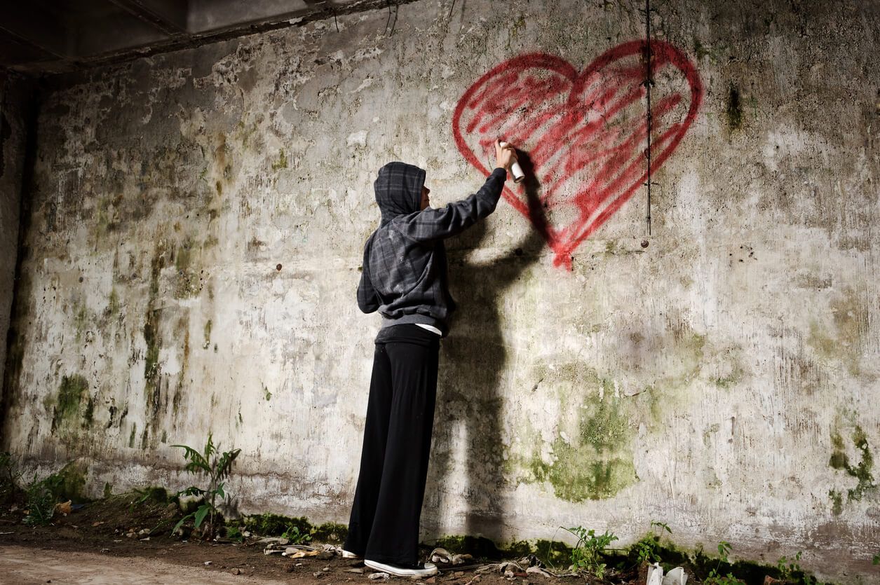 Un chico pintando un corazón en una pared.