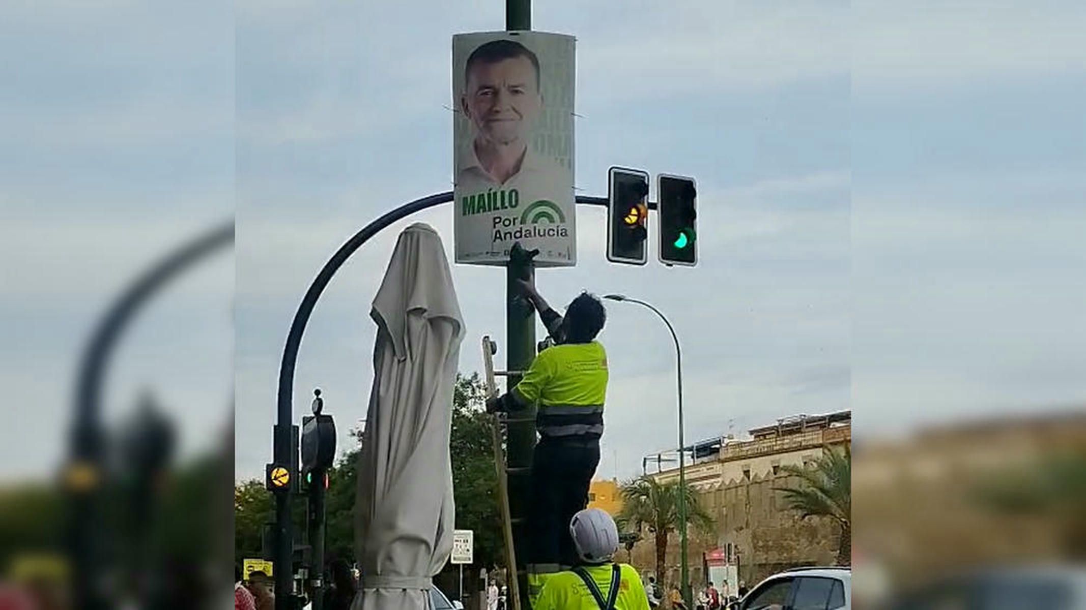 Operarios municipales de Sevilla retirando carteles electorales de Por Andalucía