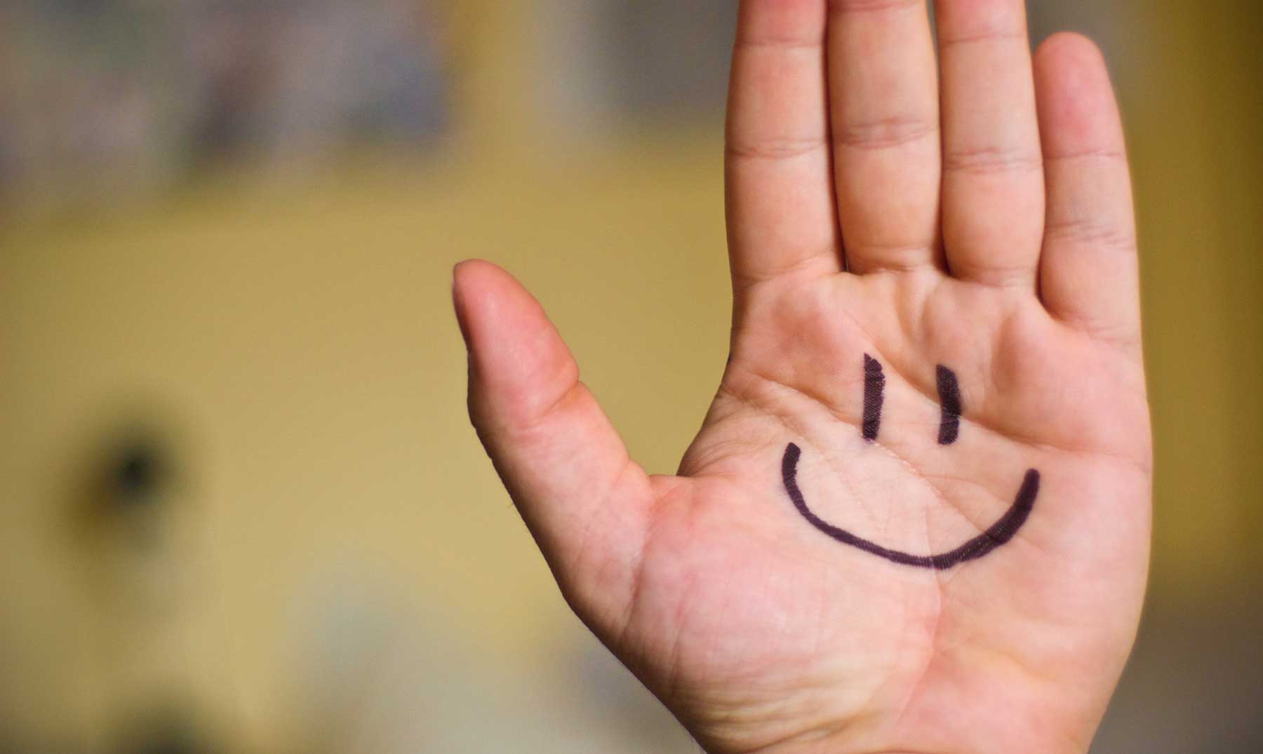 Una mano pintada con una sonrisa.  'Yellow Day', las razones porque los científicos nombran este lunes el día más feliz del año