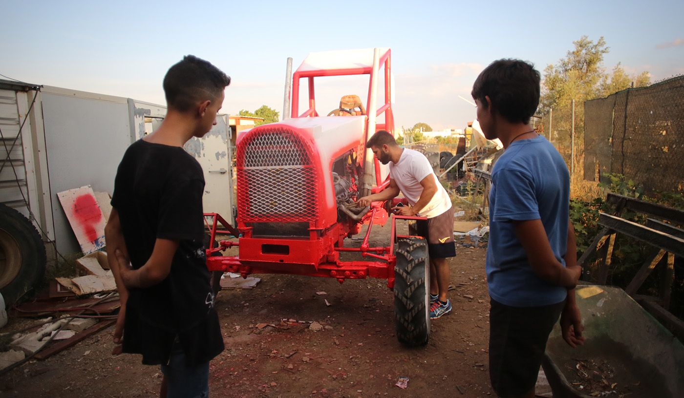 Dos jóvenes miran cómo se repara un tractor. FOTO: JUAN CARLOS TORO.