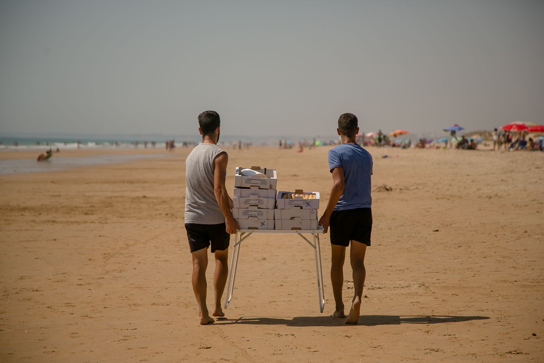 Dos jóvenes, cargando dulces por una de las playas de la provincia de Cádiz. FOTO: JUAN CARLOS TORO