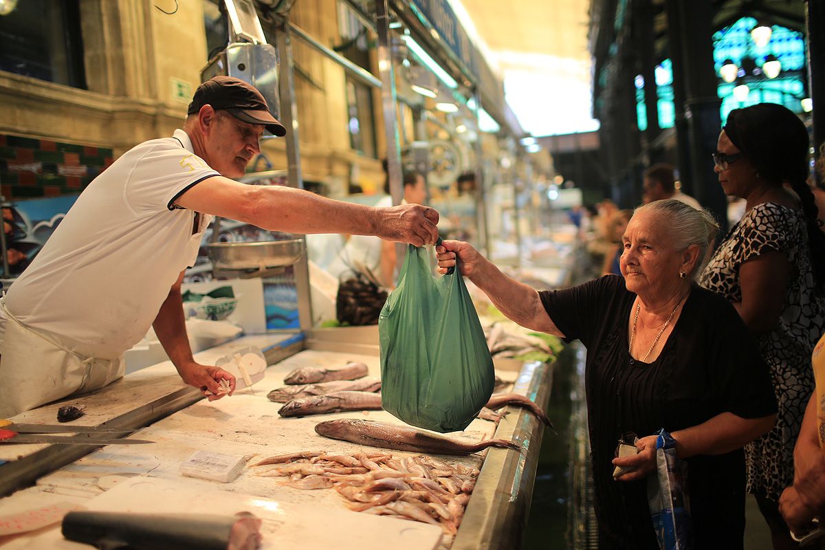 Un pescadero de la plaza de Abastos de Jerez, sirviendo a una clienta. FOTO: JUAN CARLOS TORO