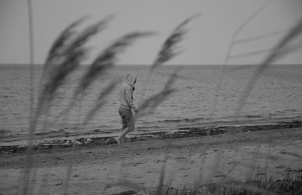 Un hombre pasea por la orilla de una playa, en una recreación sobre situaciones de salud mental.