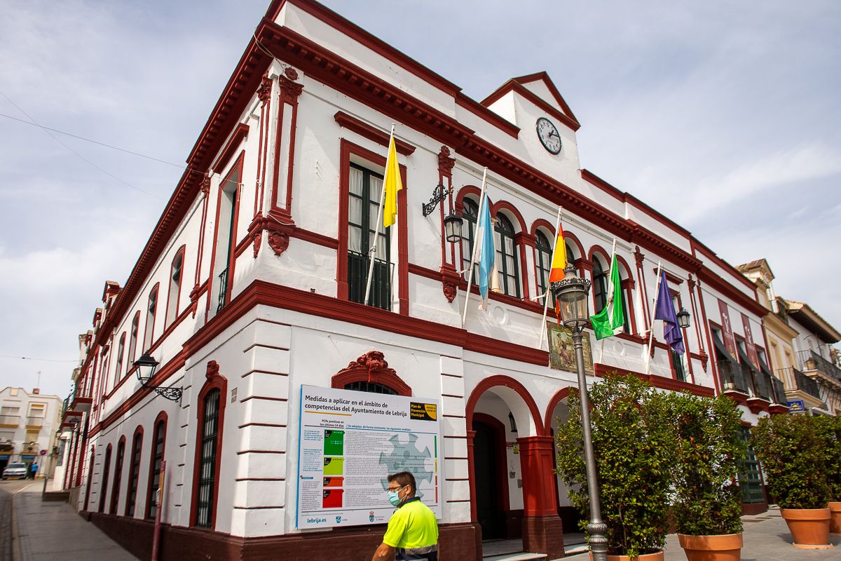 Un operario pasa por el Ayuntamiento de Lebrija, donde ondea la bandera amarilla.
