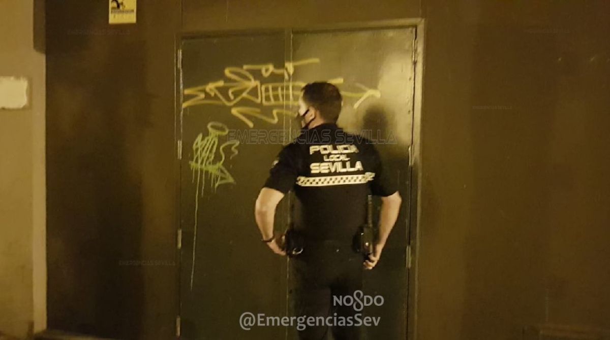 Un agente de la Policía Local de Sevilla en la puerta del bar precintado con 13 personas fumando sin mascarillas